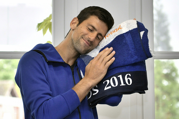 Serbia's Novak Djokovic smiles with a towel embroidered with his name after cutting his birthday cake at the Roland Garros 2016 French Tennis Open in Paris on May 22, 2016. / AFP / Philippe LOPEZ (Photo credit should read PHILIPPE LOPEZ/AFP/Getty Images)